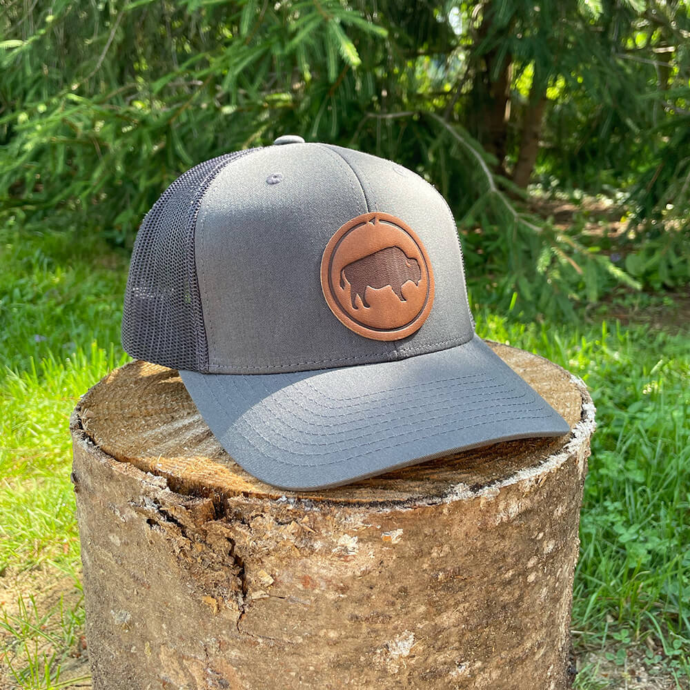 Brown and khaki trucker hat with full-grain leather patch of Bison | BLACK-004-010, CHARC-004-010, NAVY-004-010, HGREY-004-010, MOSS-004-010, BROWN-004-010
