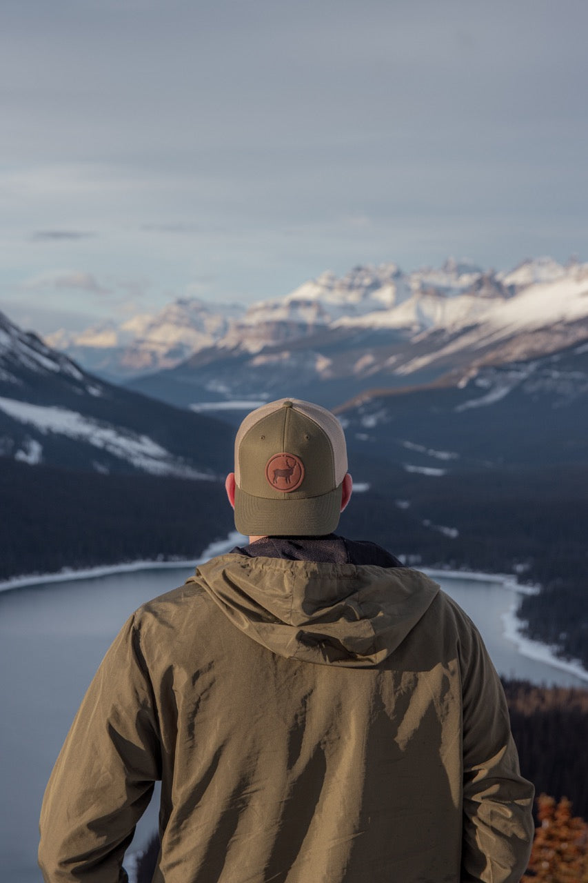 moss green trucker hat with a leather patch of an elk