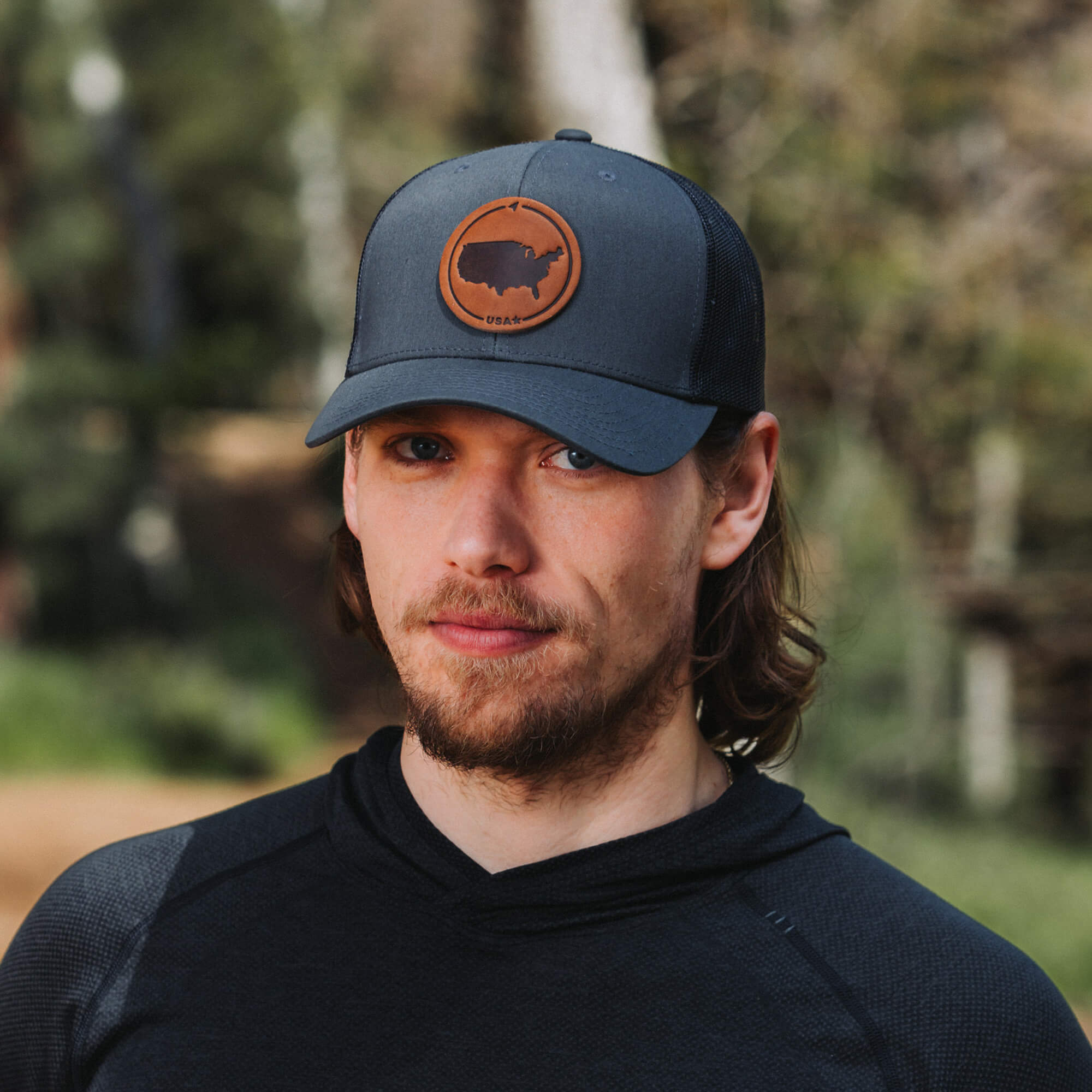 Charcoal trucker hat with full-grain leather patch of a Michigan | BLACK-003-007, CHARC-003-007, NAVY-003-007, HGREY-003-007, MOSS-003-007, BROWN-003-007