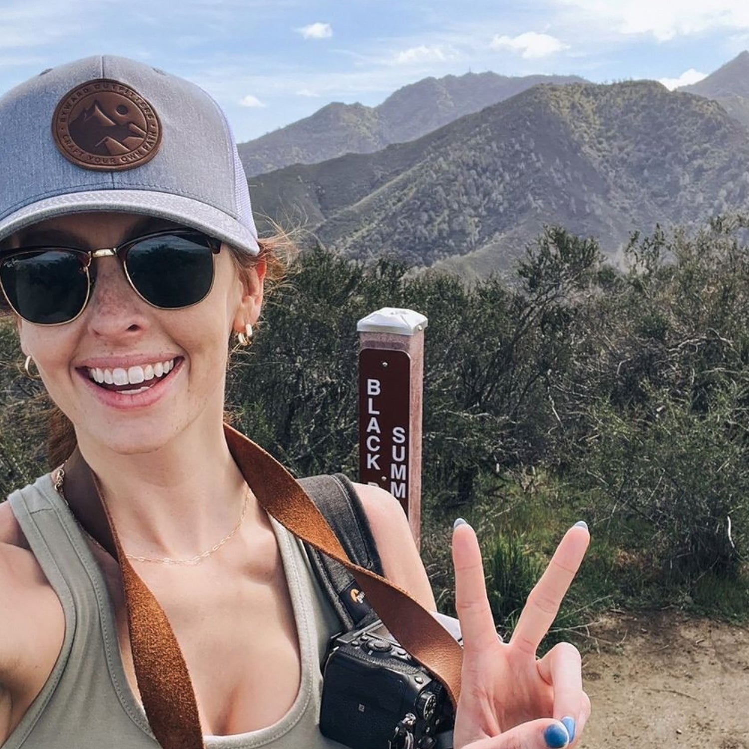 leather patch trucker hat worn at the top of a mountain outdoor hike