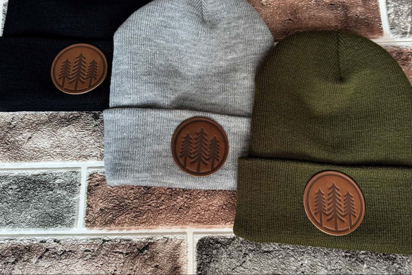 Three custom toques in black, gray, and olive with a tree logo on a leather patch