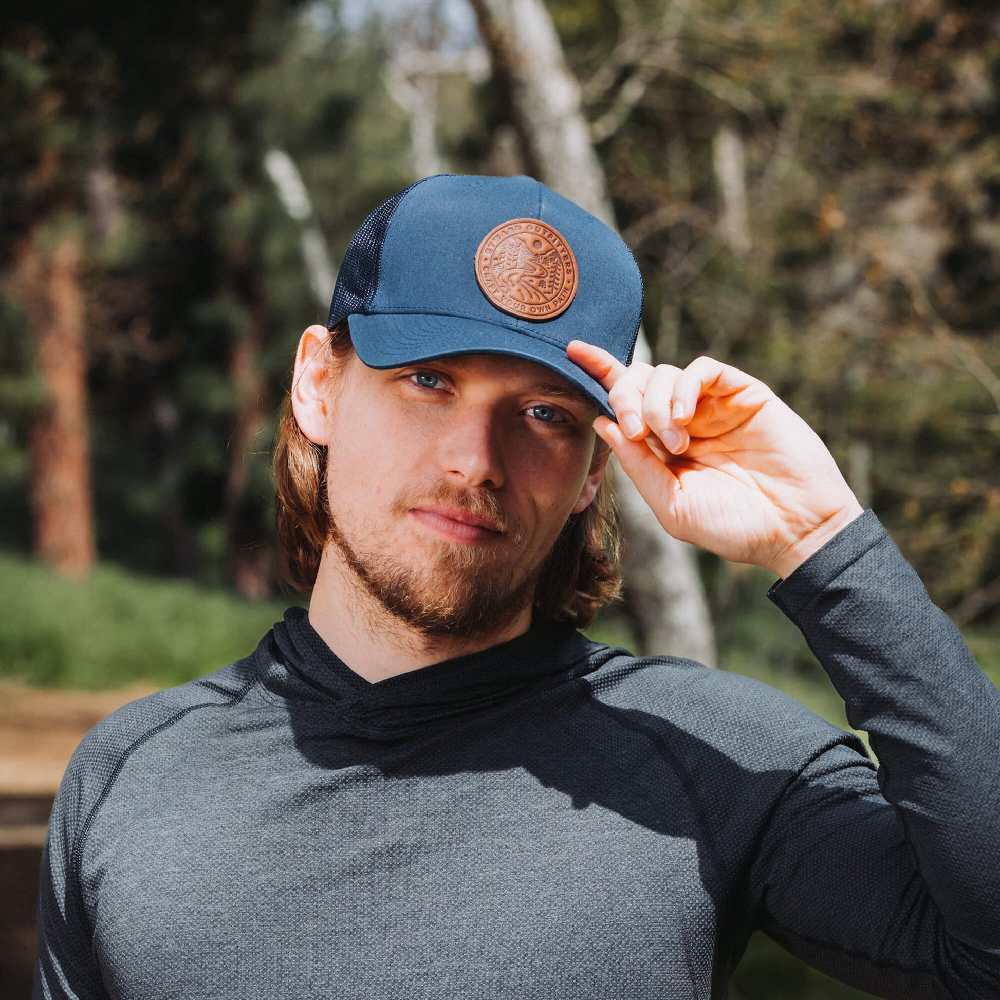 Navy trucker hat with full-grain leather patch of Winding Wilderness | BLACK-005-004, CHARC-005-004, NAVY-005-004, HGREY-005-004, MOSS-005-004, BROWN-005-004